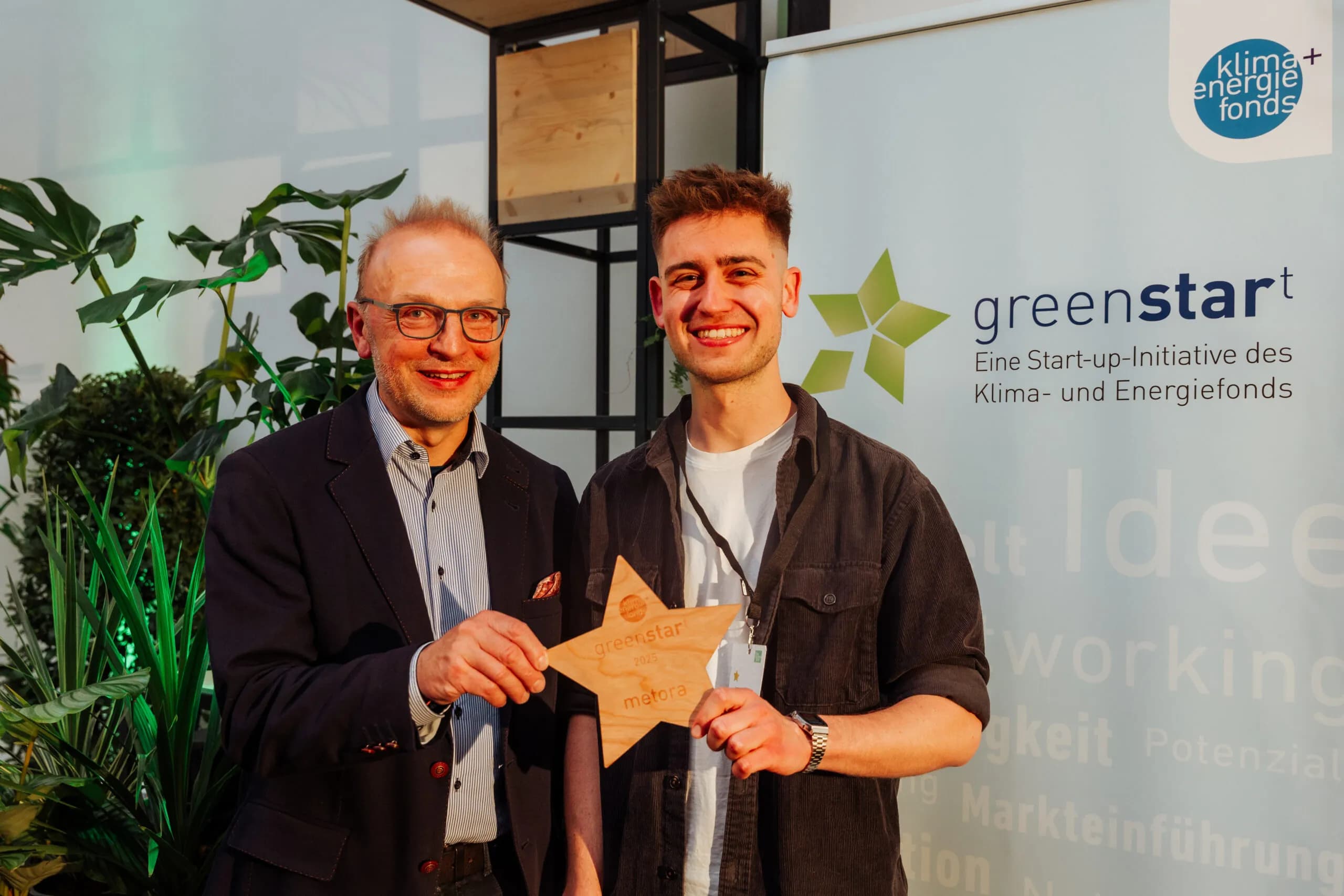 Laurenz Birnbaum and another person holding the wooden greenstart star reading “greenstart 2025 metora”